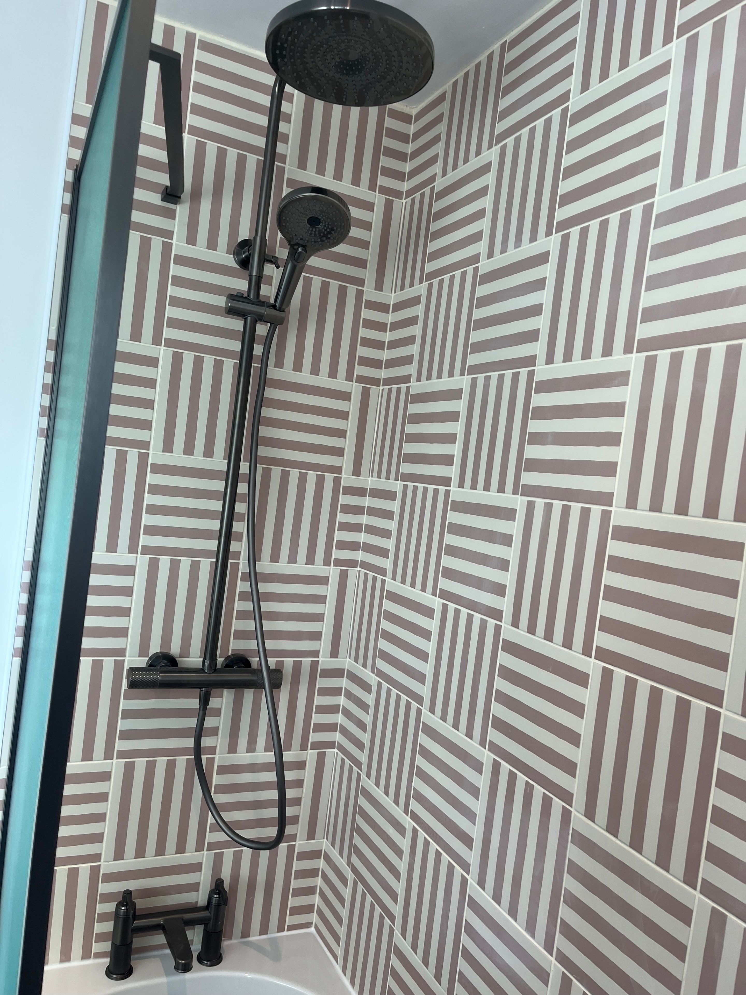 Shower area with striped tile ceiling and matte black fittings