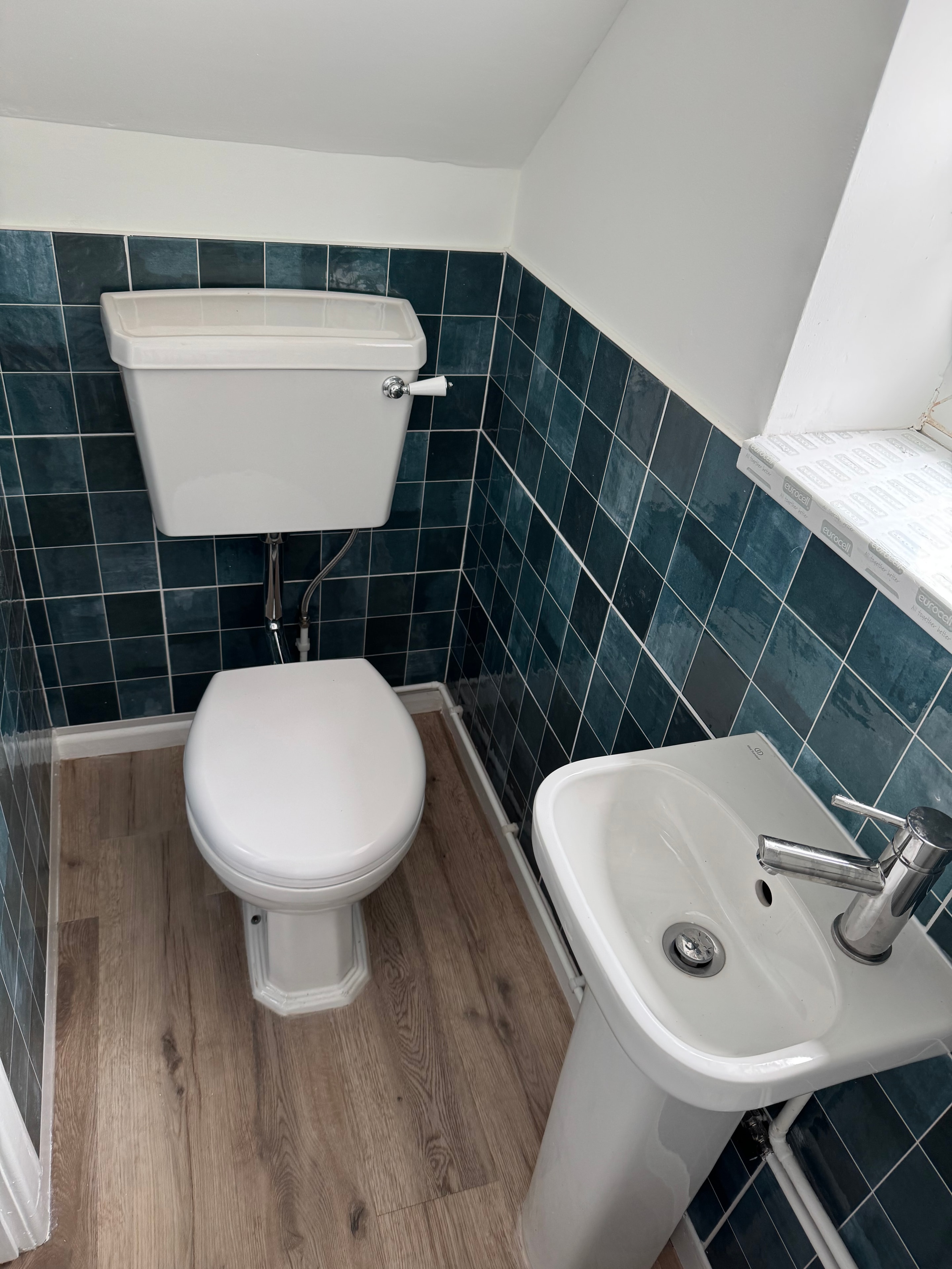 Cloakroom with teal wall tiles, LVT flooring and white suite