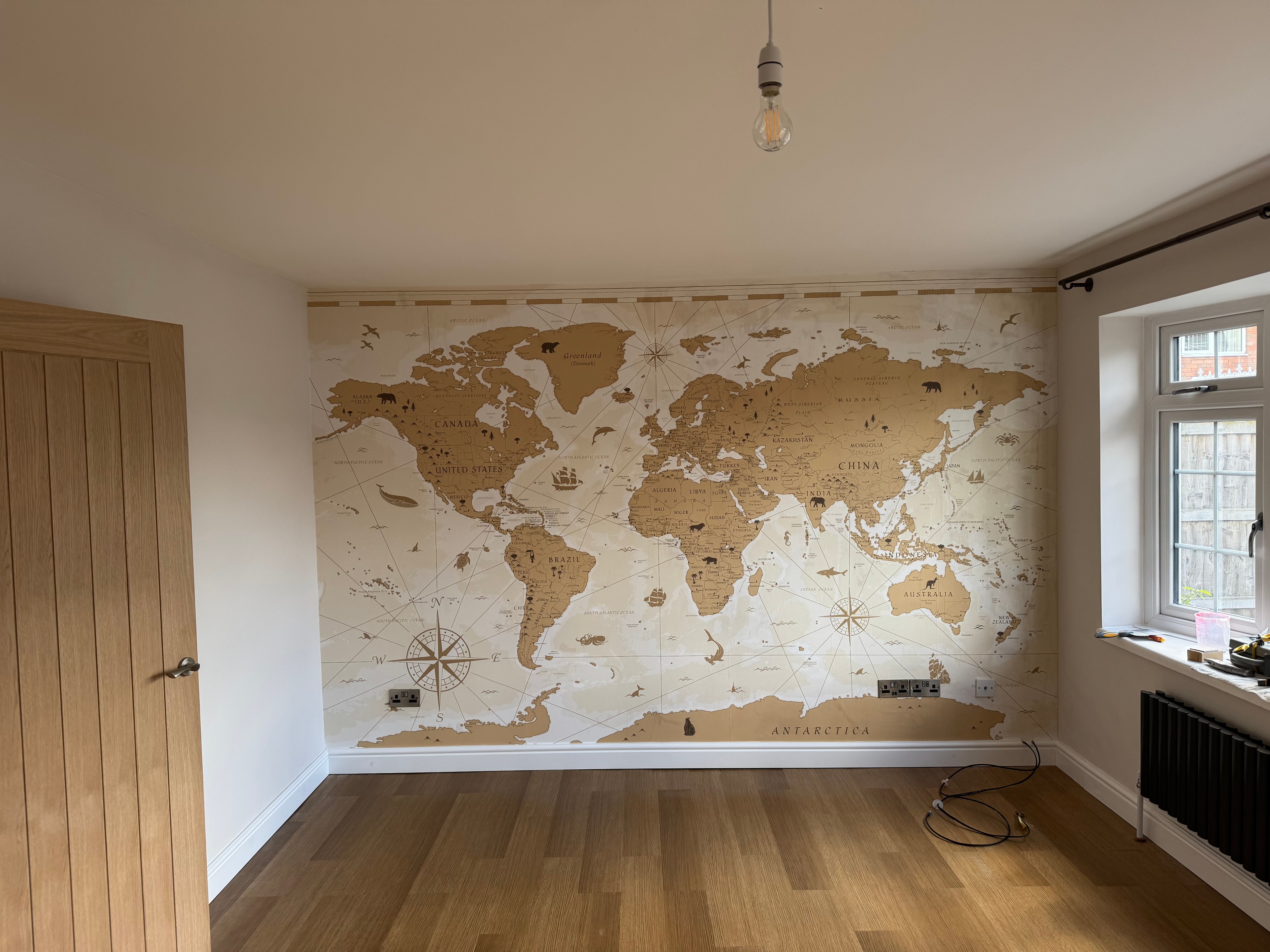 World map feature wall mural being hung — in progress